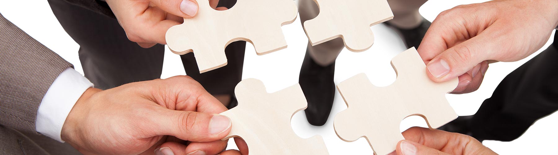 four people each holding a large puzzle piece towards each other